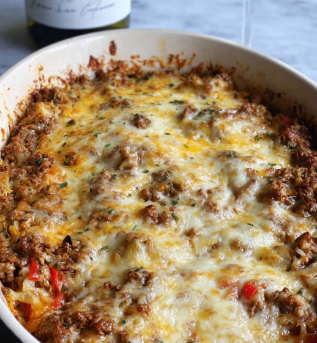 A close-up view of a white oval baking dish filled with a layered casserole topped with melted cheese. The top layer has a mix of creamy white and golden-yellow melted cheese that covers a chunky, browned mixture of ground meat and small bits of vegetables like red and green peppers, giving a textured and slightly crispy look around the edges. In the background on a white marbled surface, there is a bottle of wine with a white label featuring black drawing and text and a tall wine glass filled with pale white wine, slightly blurred to keep focus on the dish. photo taken with an iphone --ar 2:3 --v 7 - Vegetarian Hatch Chile Enchiladas, Hatch Chile Enchiladas, Vegetarian Enchiladas with Hatch Chiles, Easy Hatch Chile Enchiladas, Roasted Hatch Chile Enchiladas