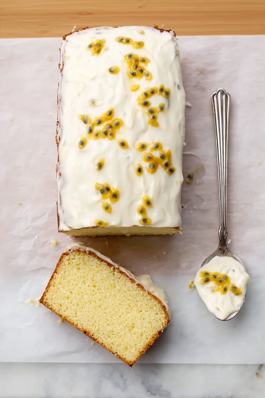 The image shows a rectangular cake with one slice lying flat in front of it. The cake has one thick layer of light yellow, slightly textured sponge as the base. It is topped with one smooth layer of white cream frosting that covers the whole cake, decorated with small yellow passion fruit seeds and bits scattered unevenly on top. To the right of the cake is an old-fashioned silver spoon with white cream and a few passion fruit seeds on it. The cake and spoon sit on white parchment paper placed on a white marbled surface. Photo taken with an iphone --ar 2:3 --v 7 - Passion Fruit Lemon Drizzle Cake, tropical lemon cake, easy citrus dessert, moist passion fruit cake, fruity drizzle cake